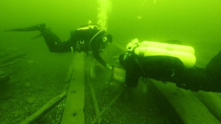 Two divers are inspecting a wreck park information sign