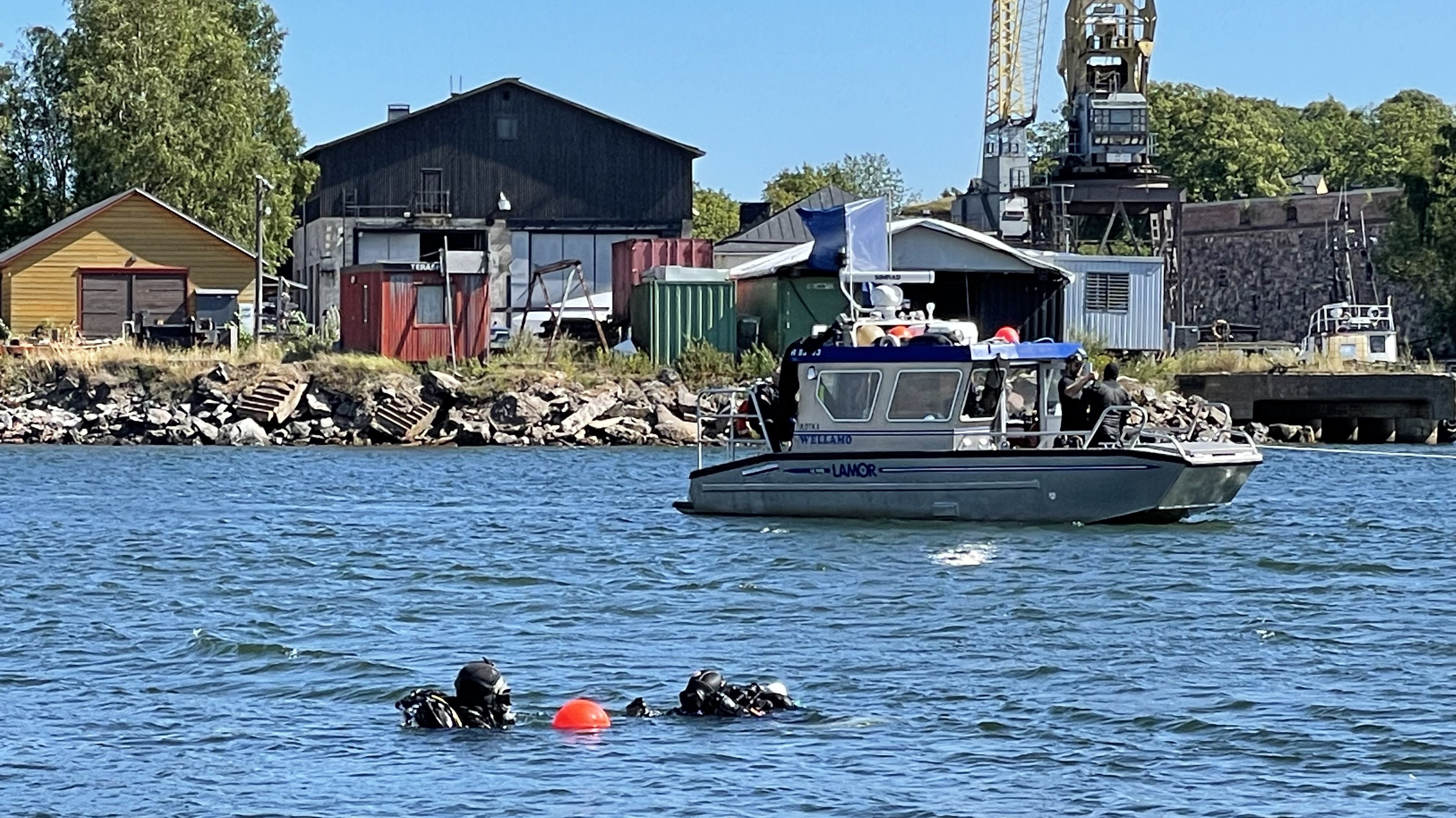 Divers on the surface at the descent line buoy. Workboat Wellamo in the background.